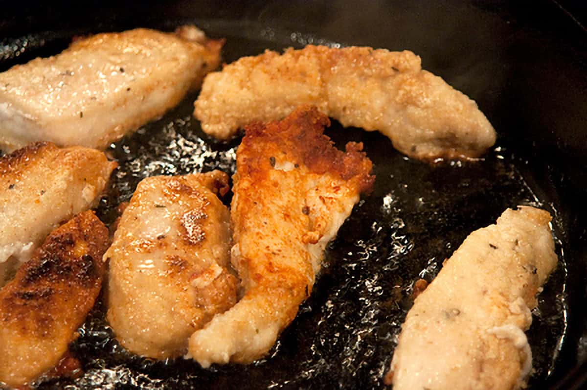 Browned chicken strips in a skillet.