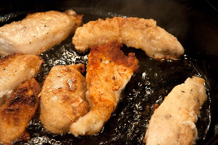 Frying chicken strips in a skillet.