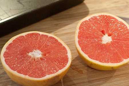 A halved grapefruit on a cutting board