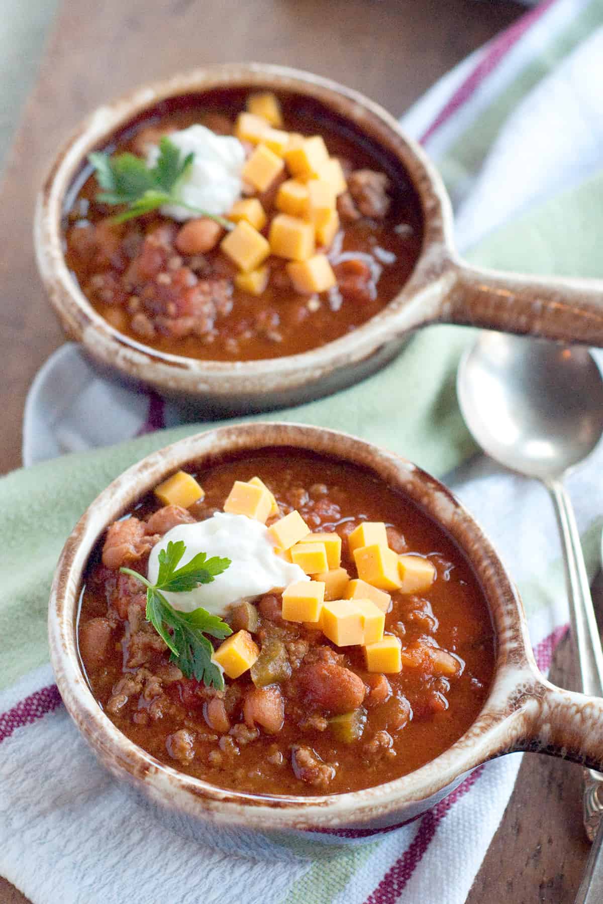 Two bowls of chili topped with sour cream and cheese.