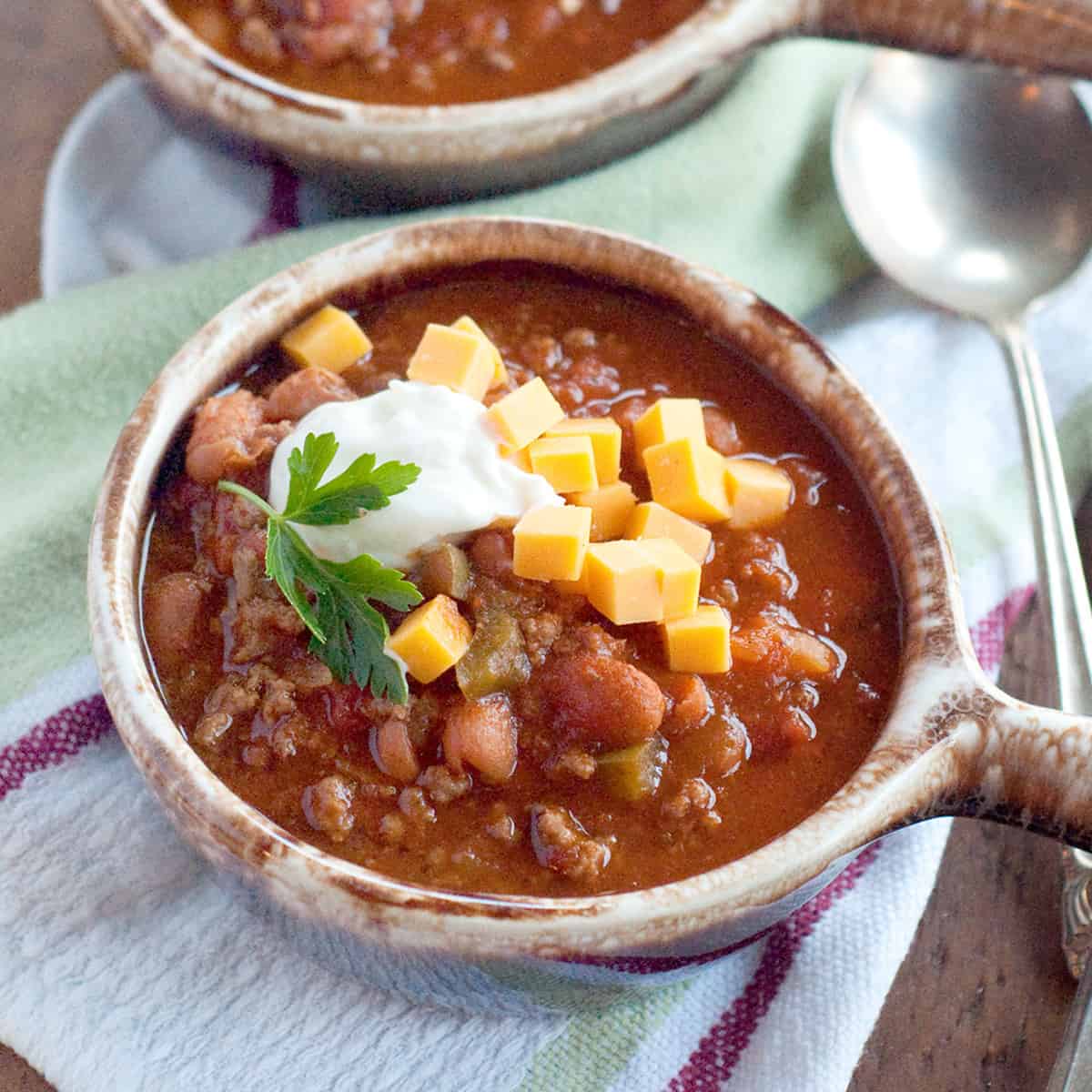 Two bowls of chili topped with sour cream and cheese.