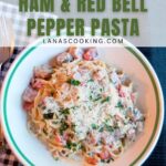 A bowl of ham and red bell pepper pasta topped with grated cheese sits on a table next to a fork, knife, and checkered napkin. Text overlay reads So Delicious! Ham & Red Bell Pepper Pasta.