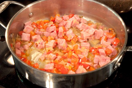 Cubed ham added to skillet with vegetables.