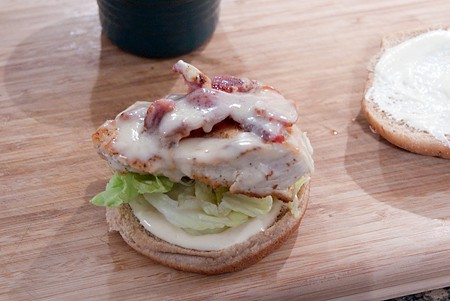Sandwiches being assembled on a wooden board.