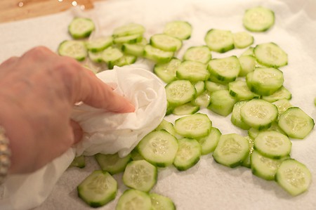 Patting the cucumbers dry with a paper towel.