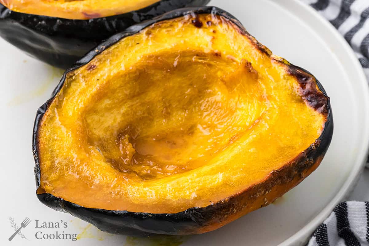 Half a baked acorn squash on a white plate.