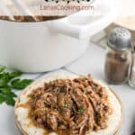 Pork ragu over buttered grits on a dinner plate.