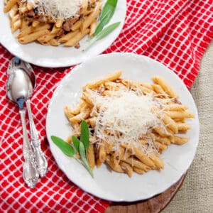 A serving of Penne with Guanciale on a white dinner plate.