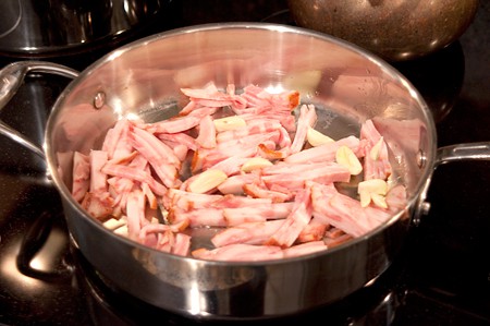 Guanciale (pig jowls) with tomatoes and garlic in a skillet.