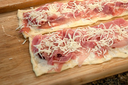Mozzarella cheese sprinkled over the prosciutto.