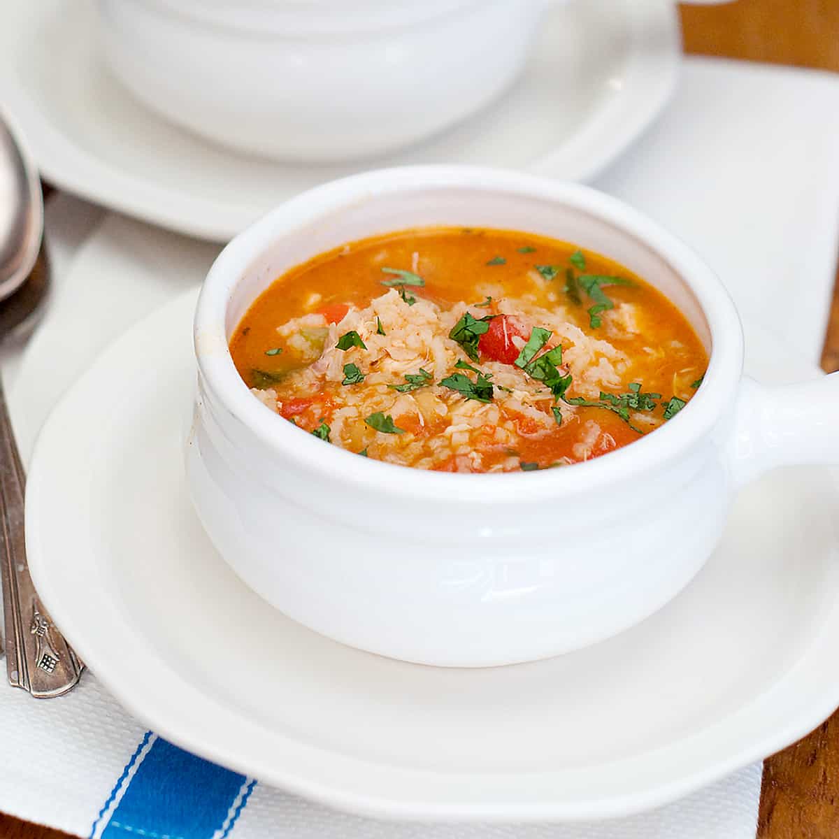 A serving of Spanish Chicken and Rice Soup in a white bowl.