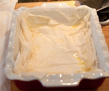 Lining a baking dish with phyllo pastry.