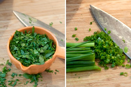 Chopped parsley and chives on a cutting board.