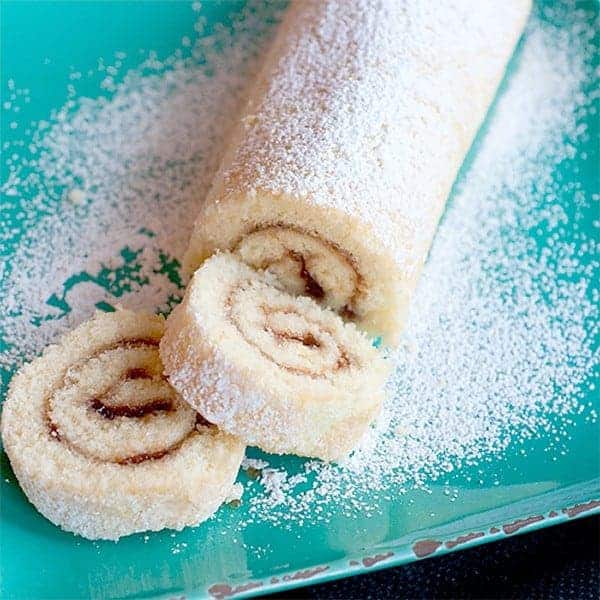 Raspberry Filled Jelly Roll - rolled and filled sponge cake sprinkled with powdered sugar. https://www.lanascooking.com/raspberry-filled-jelly-roll/