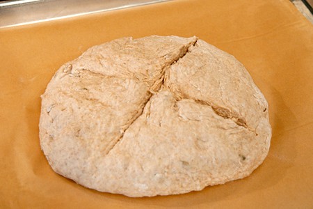 Round of dough slashed and pricked and sitting on parchment paper on a baking sheet