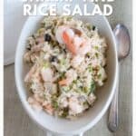 Bowl of shrimp and rice salad with vegetables, served with a spoon on a light tablecloth.