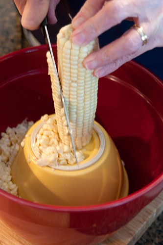 Cutting kernels from an ear of corn.