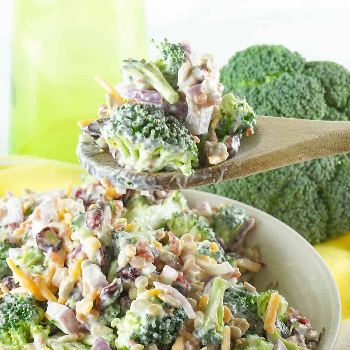 A wooden spoon holding a bite of broccoli salad.
