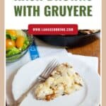 A plate of hash browns with Gruyere cheese, served with a fork, next to a fresh salad.