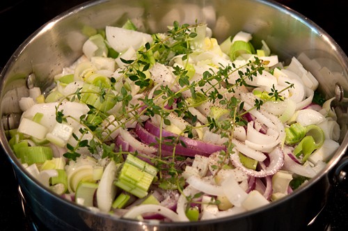 Prepared onions with butter, oil, and seasonings in a skillet.