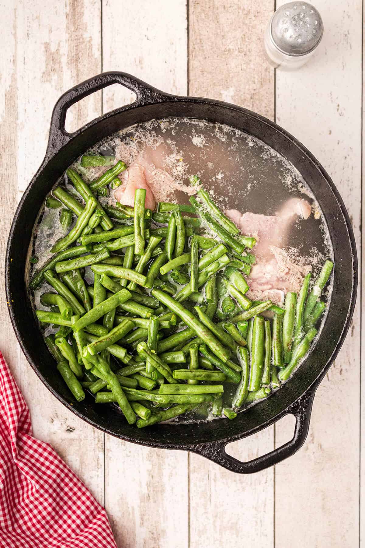Cast iron cooking pot with ham hock broth and fresh green beans added.