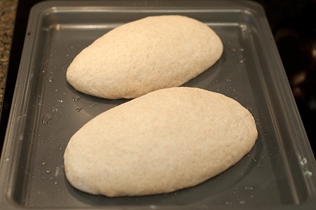 Two formed loaves of bread on a baking sheet.