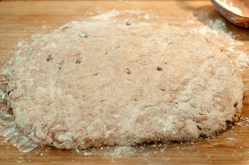 Dough patted out into a circle on a cutting board.