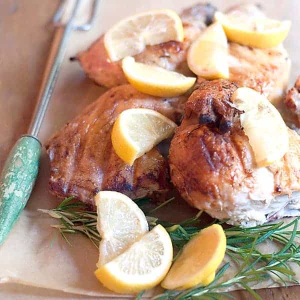Rosemary Lemon Spatchcocked Chicken - butterflied chicken marinated in olive oil, rosemary, and lemon - cooked under a weight on an outdoors grill. https://www.lanascooking.com/rosemary-lemon-spatchcocked-chicken-recipe/