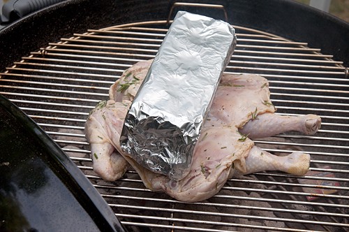 Cooking the chicken on a grill weighted with a brick.