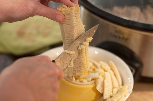 Cutting kernels from ears of blanched corn.