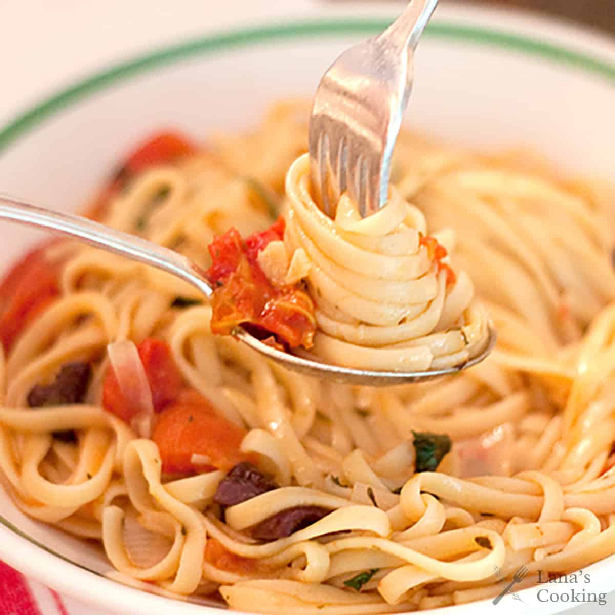 Pasta twirled on a fork inside a spoon.