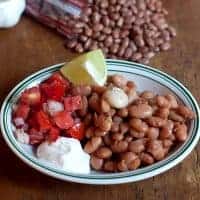 Pinto Beans with Fresh Tomato Relish - easy and simple recipe for traditional pinto beans. Served with a fresh tomato relish, sour cream, and lime wedges. https://www.lanascooking.com/pinto-beans-fresh-tomato-relish/