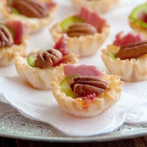 Phyllo Cups with Pepper Jelly and Brie - delicate phyllo pastry filled with pepper jelly and brie, baked and topped with pecans, country ham, and jalapeno. https://www.lanascooking.com/phyllo-cups-pepper-jelly-brie/