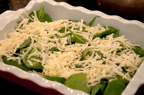 Half the grated cheese layered over the spinach in the baking dish.
