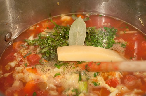 Stock, tomatoes, and herbs added to the soup pot.