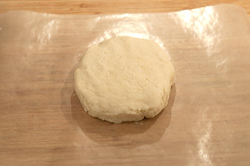 Dough formed into a round on a piece of waxed paper.