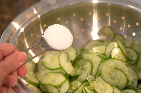 Salting the cucumber slices in a colander.
