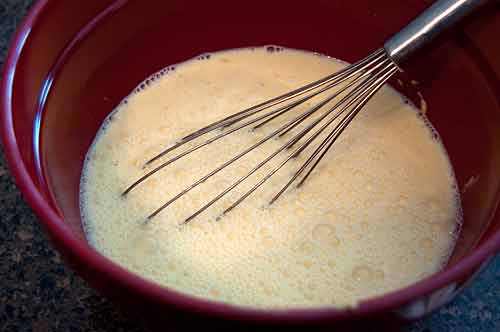 Making egg-milk mixture in a mixing bowl.