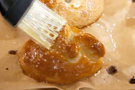 Brushing baked pretzels with melted butter.