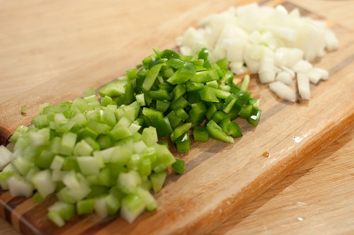 Prepping onion, celery, and bell pepper on a cutting board.