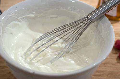 Whipped cream and a whisk in a mixing bowl.