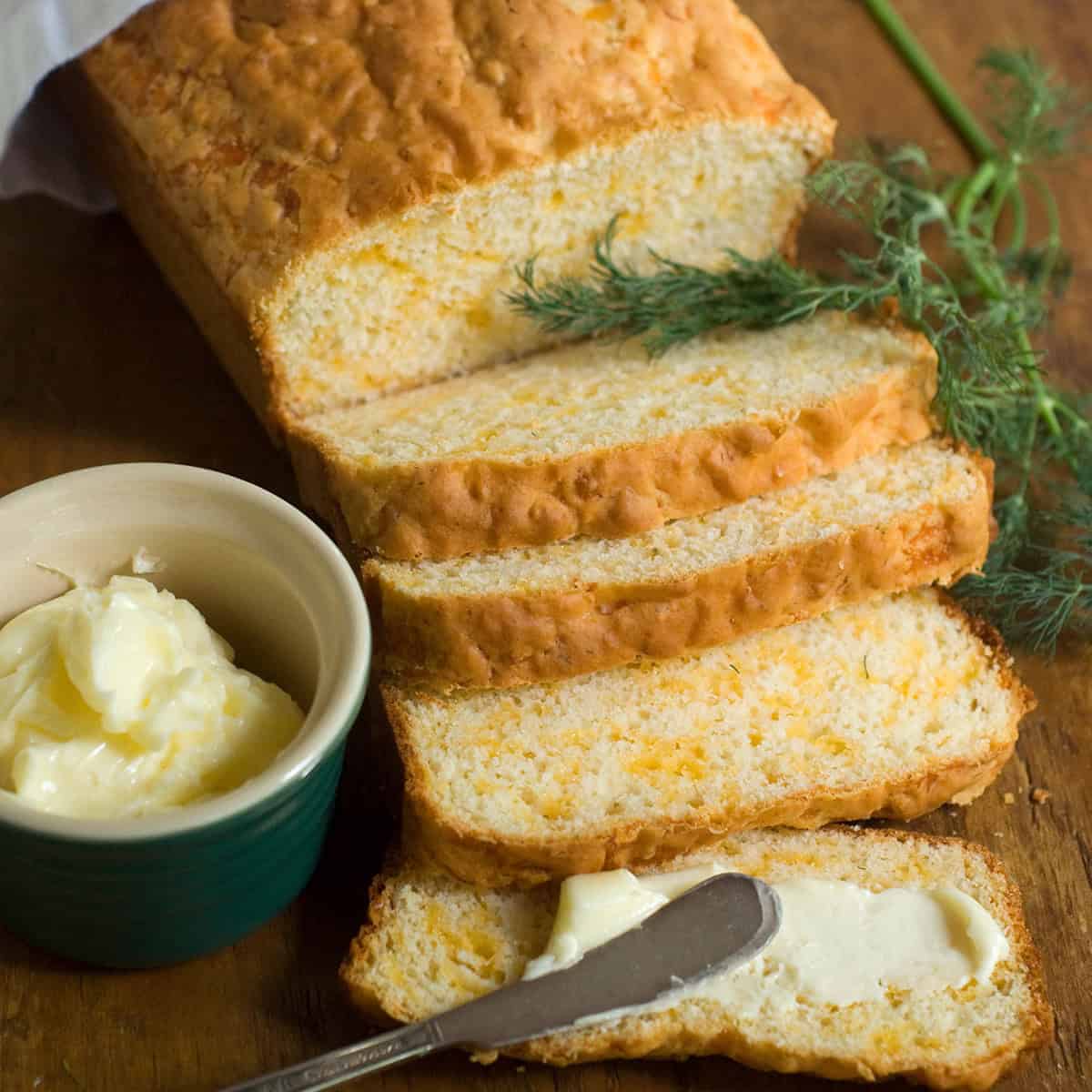 A loaf of cheddar dill quick bread on a wooden board.