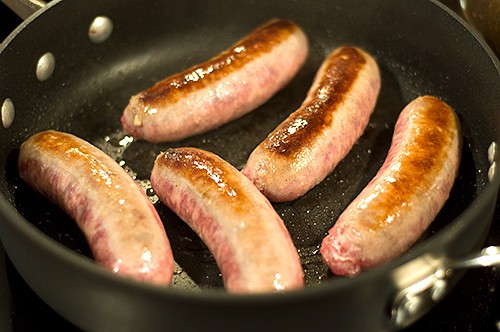 Browning brats in a skillet.