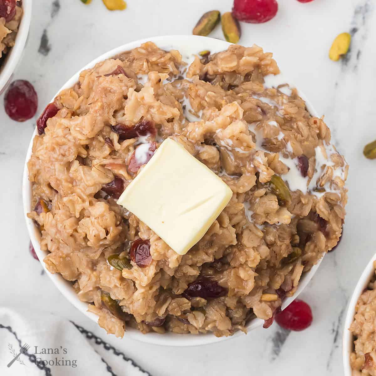 A serving of oatmeal topped with butter and cream in a white bowl.