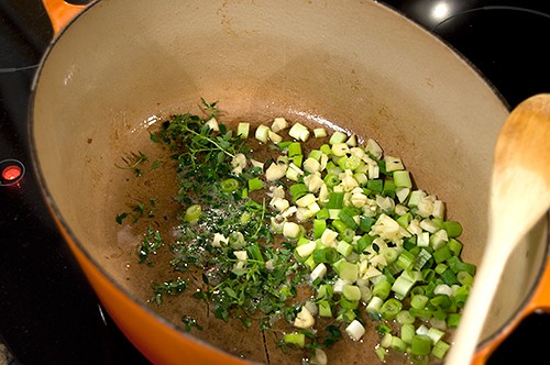 Green onions, garlic, and thyme added to the bacon drippings in a pan.