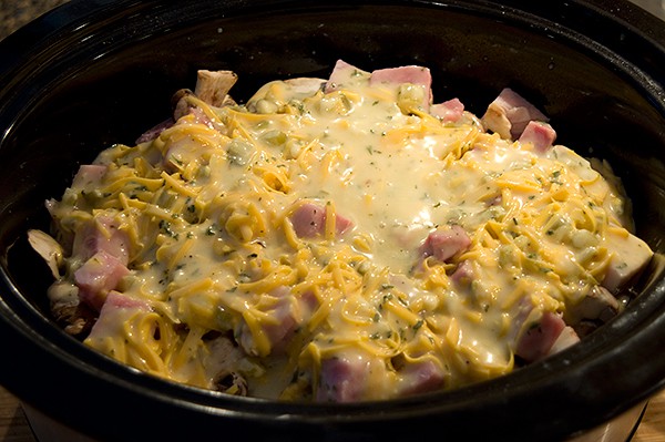 Soup mixture poured over layered ingredients in a slow cooker.