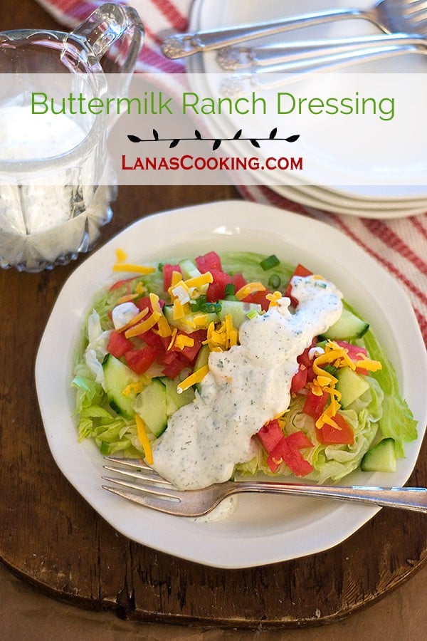 Mixed green salad on a plate with buttermilk ranch dressing poured over.