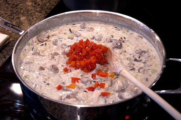 Adding cooked rice mix and other ingredients to the sauce mixture in a skillet.