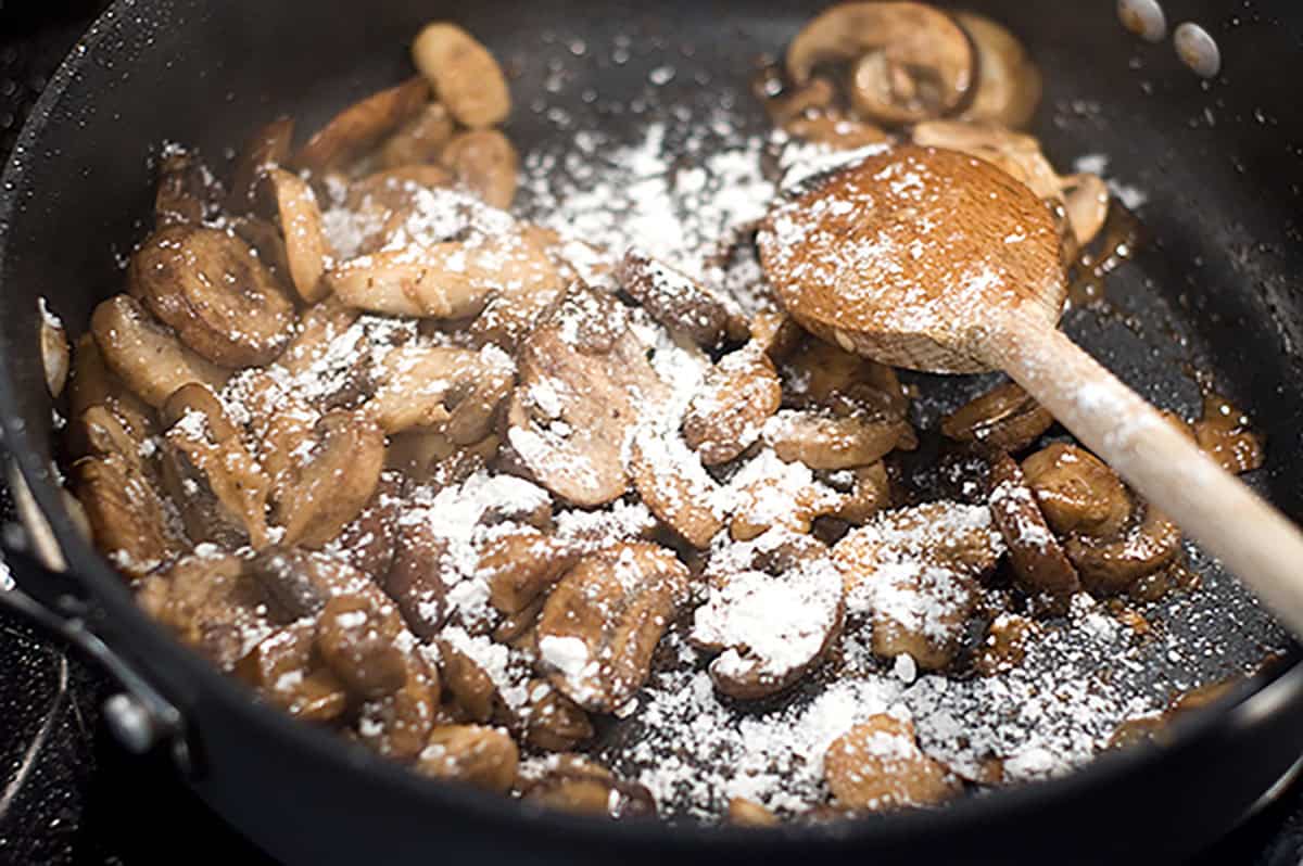 Mushrooms coated with flour in a skillet.