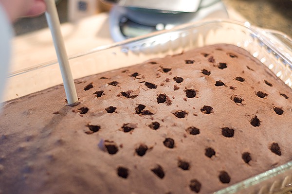 Poking holes in the baked cake.